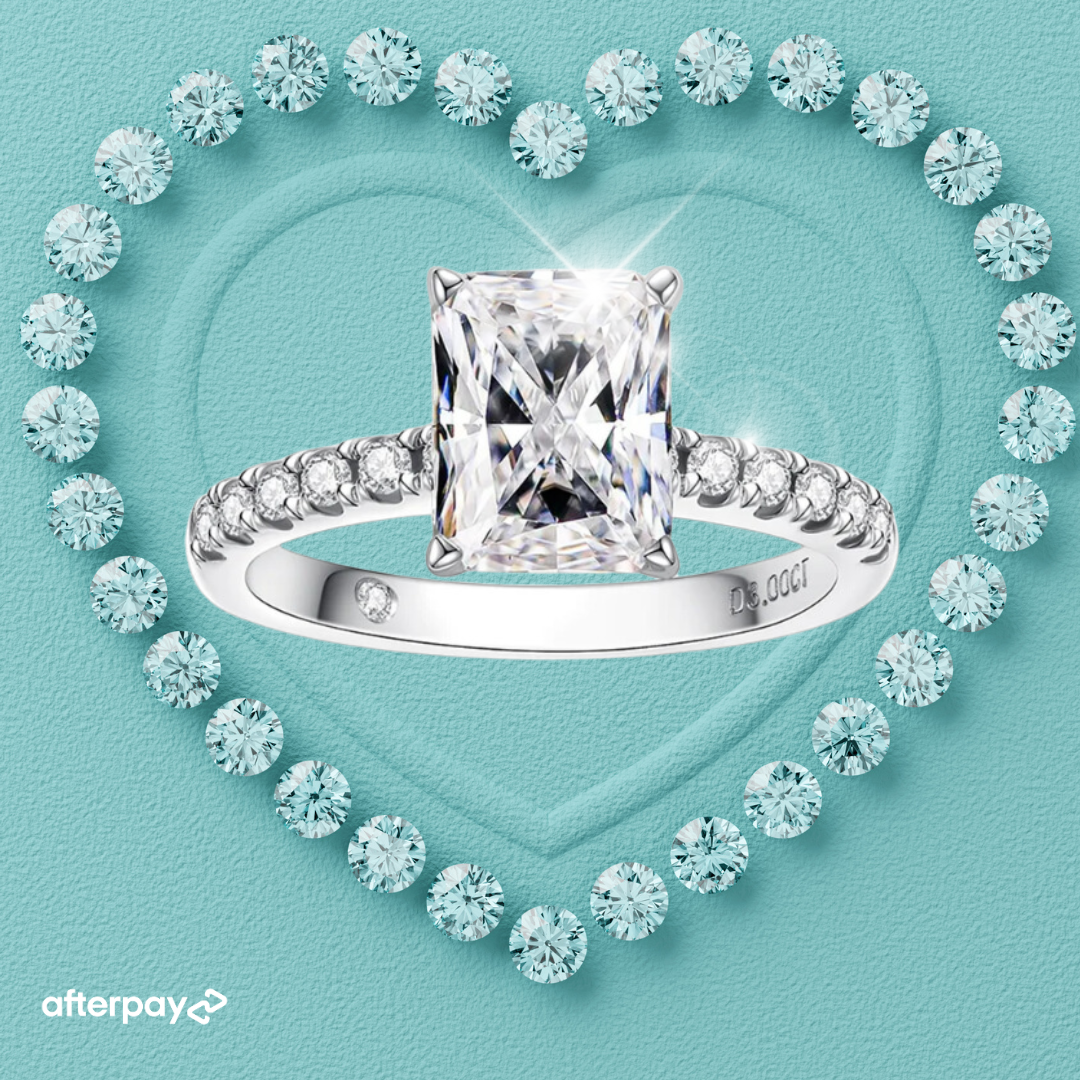 A radiant cut moissanite ring with diamond accents on the band, displayed on a heart-shaped background with diamond patterns.