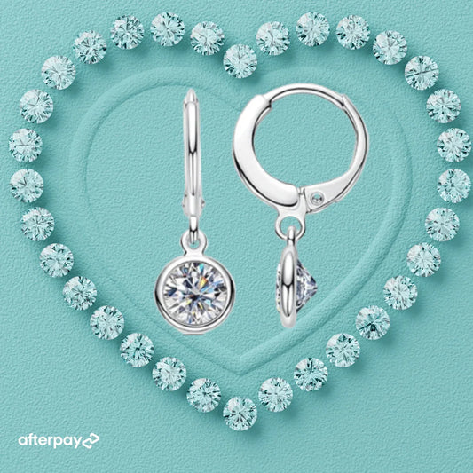 Silver drop earrings with moissanite gemstones on a turquoise background with Afterpay logo.