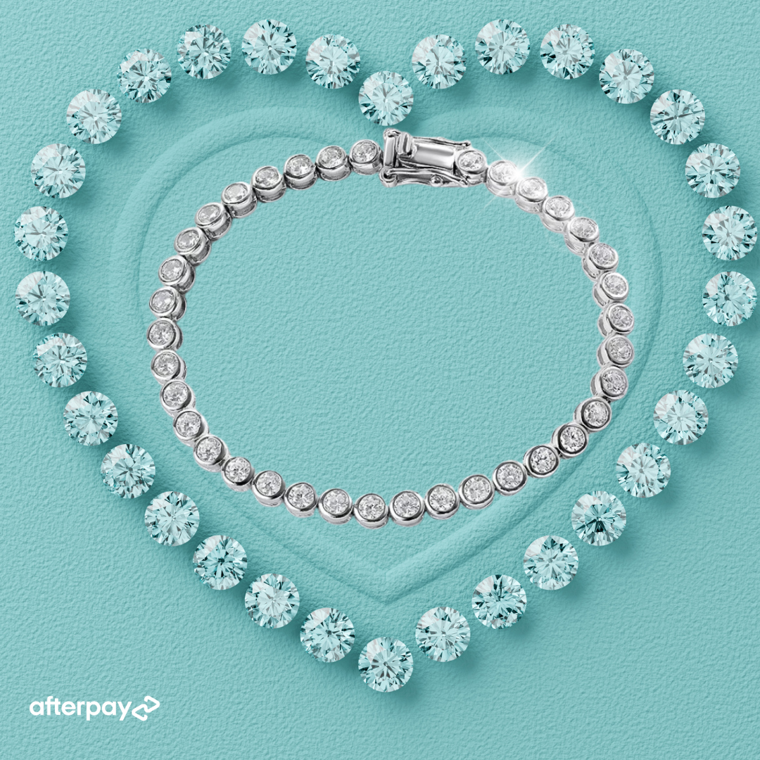 A tennis bracelet featuring round brilliant-cut moissanite stones set in a bezel design, displayed on a heart-shaped background.