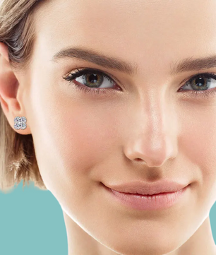 Close-up of a woman wearing a diamond earring against a light blue background