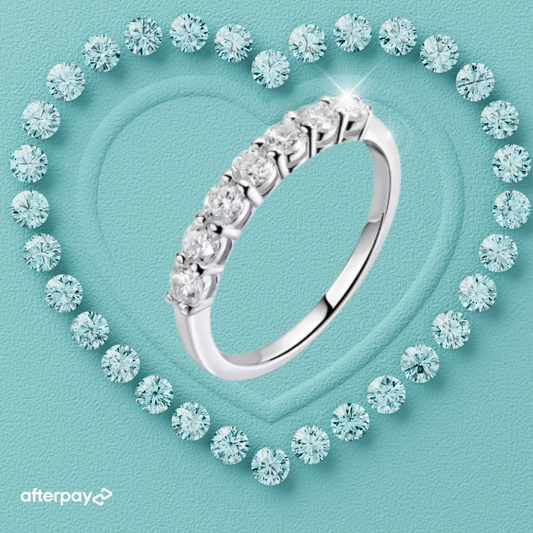 Moissanite wedding band surrounded by smaller diamonds on a light blue background with Afterpay logo.