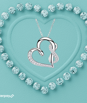 Silver heart-shaped pendant necklace on a turquoise background with diamond-like crystals forming a heart shape.