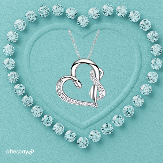Silver heart-shaped pendant necklace on a turquoise background with diamond-like crystals forming a heart shape.