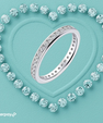 A silver-tone eternity ring set with clear round-cut gemstones, arranged on a textured aqua background with a heart outline made of matching stones. An Afterpay logo appears in the bottom-left corner.