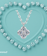 A silver-toned necklace with a four-petal flower pendant set with clear gemstones, centered on a textured aqua background with a heart outline made of matching round clear stones. An afterpay logo appears in the lower-left corner.