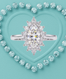 A silver-tone ring with a large marquise-cut clear center stone and surrounding halo-style round stones, centered on a turquoise textured background with a heart outline made of matching stones.