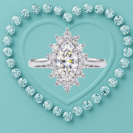 A silver-tone ring with a large marquise-cut clear center stone and surrounding halo-style round stones, centered on a turquoise textured background with a heart outline made of matching stones.
