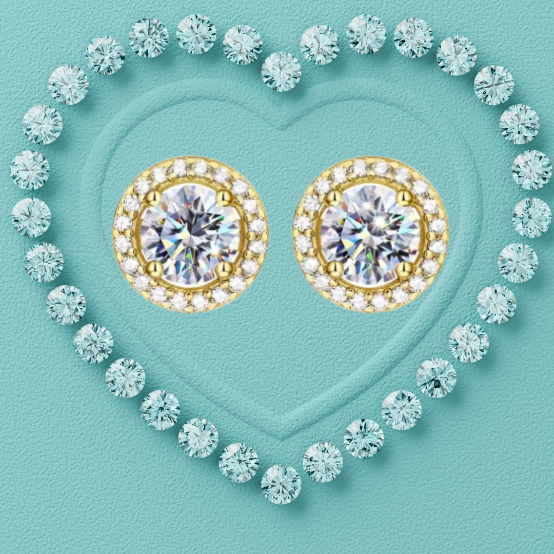 A pair of gold stud earrings with large round clear center stones surrounded by small clear stones, arranged inside a heart outline made of light blue gemstones on a turquoise background.