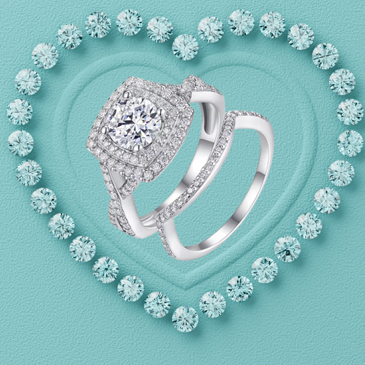 A silver-toned double ring set with pavé diamonds, featuring a square halo ring and a matching band, displayed on a textured turquoise background with a heart outline of round diamonds.