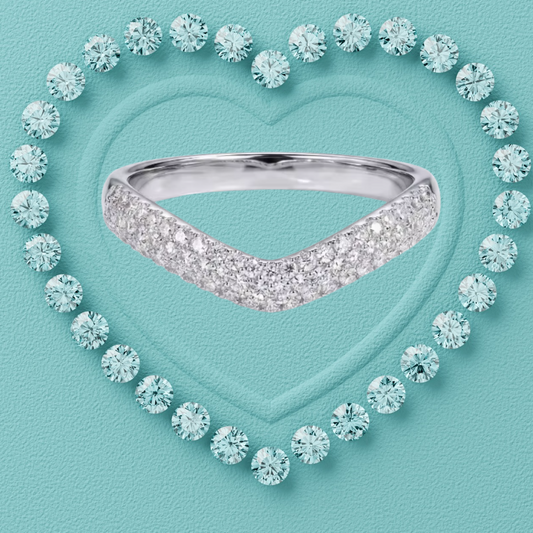 A silver V-shaped diamond ring centered inside a heart outline made of round light blue gemstones on a textured turquoise background.