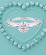 Saturn’s Kiss moissanite ring featuring a round centre stone crossed by a polished silver-toned band, with small side stones.