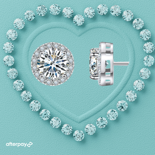 A pair of round moissanite halo earrings set in white gold-plated S925 silver, displayed within a heart-shaped arrangement of blue crystals.