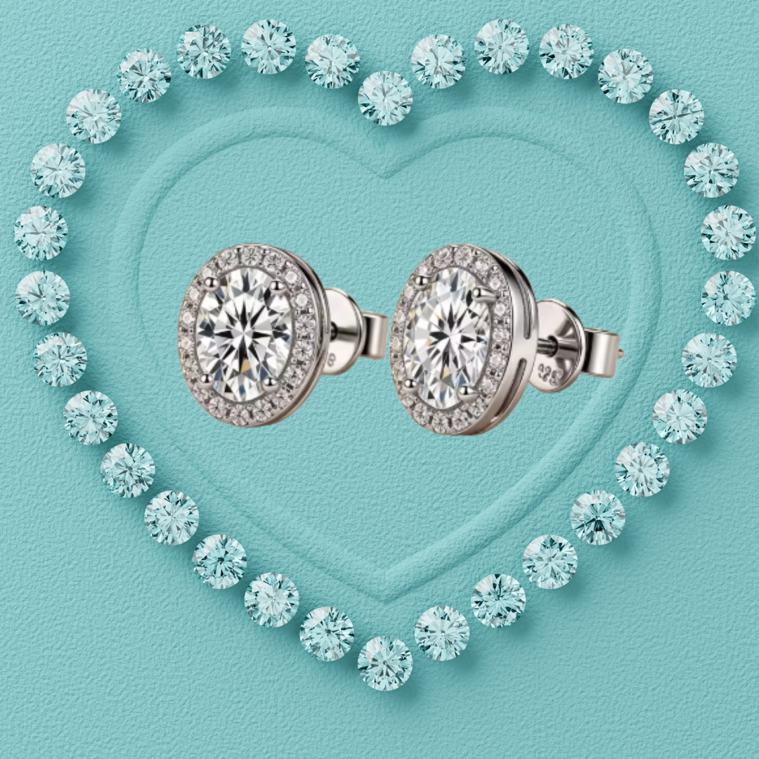 A pair of round diamond halo stud earrings in silver-toned metal, arranged side by side on a textured turquoise background with a heart outline made of small diamonds.