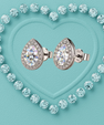 Pear-shaped diamond stud earrings in a silver-toned setting, surrounded by a heart-shaped border of round clear stones on a textured light blue background.