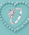 A silver-toned ring with three large clear rectangular-cut gemstones, centered against a turquoise background with a heart outline made of small matching stones.