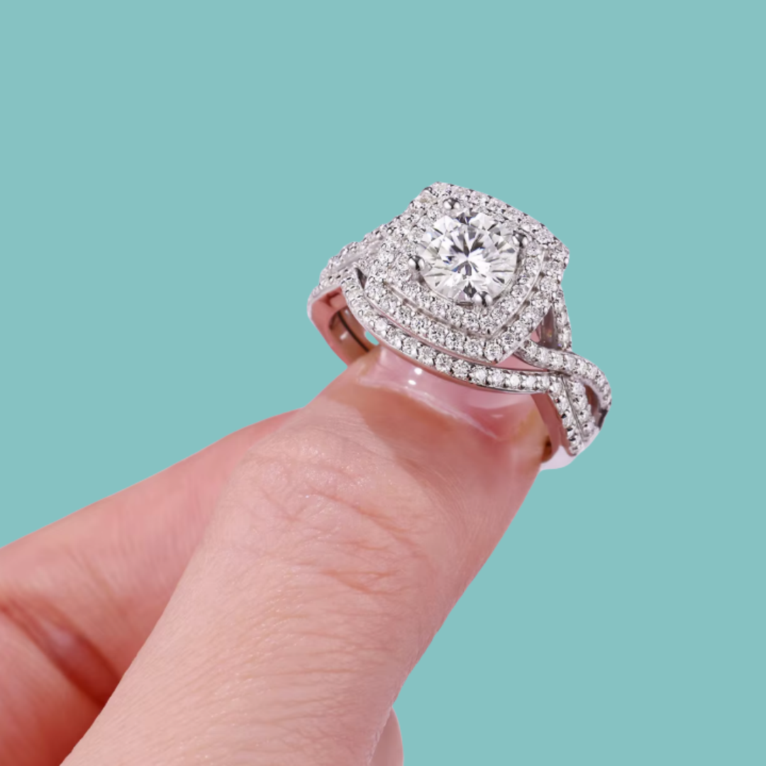 A close-up of a halo diamond ring with a square-cut center stone and surrounding pavé bands, shown being worn on a finger against a solid teal background.