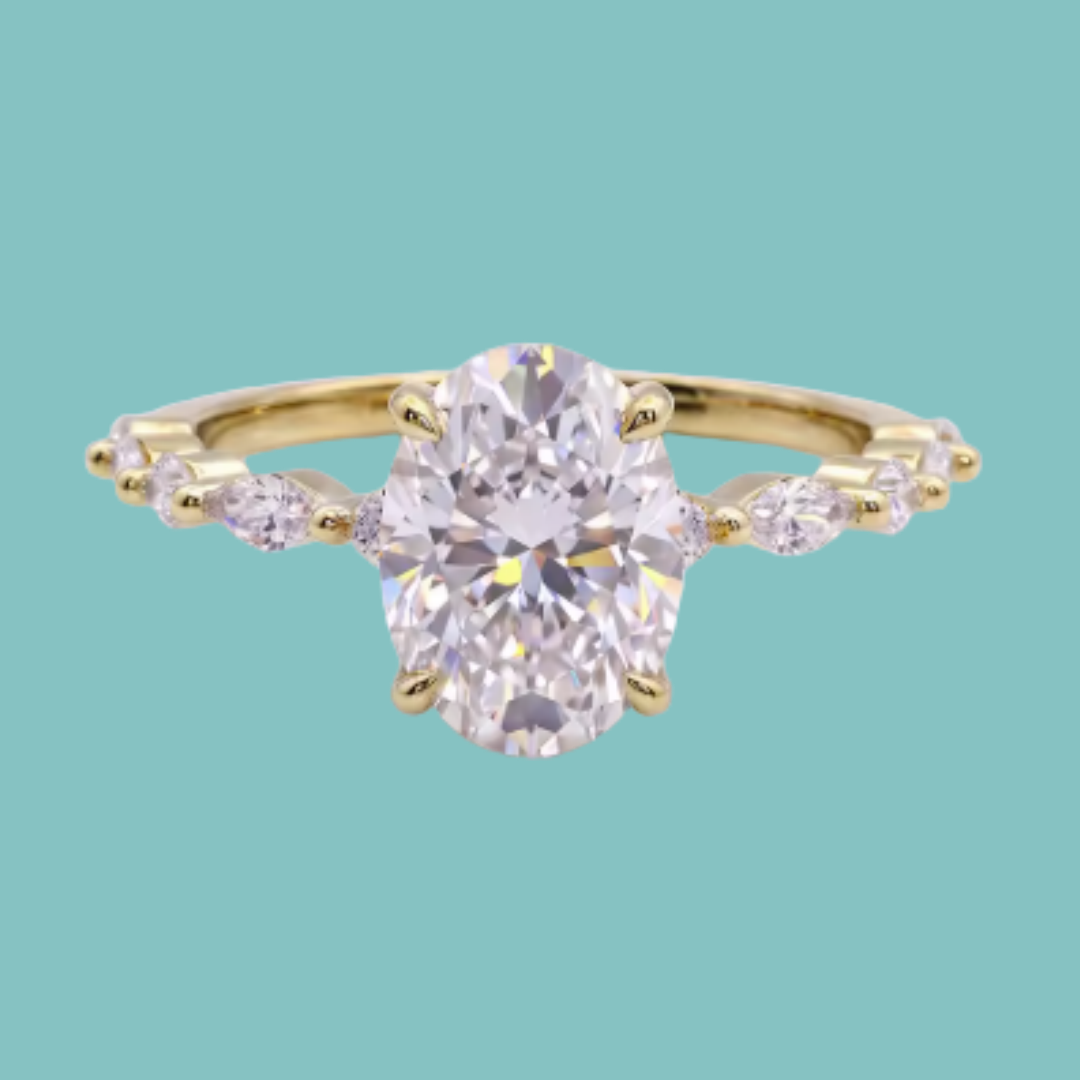 A yellow gold ring featuring a large oval-cut clear center stone and smaller marquise-cut side stones, shown on a solid light teal background.