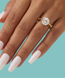 Saturn’s Kiss moissanite ring featuring a round centre stone crossed by a polished gold-toned band on a models hand with small side stones.