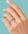 A close-up of a hand wearing a silver diamond eternity ring against a solid teal background.