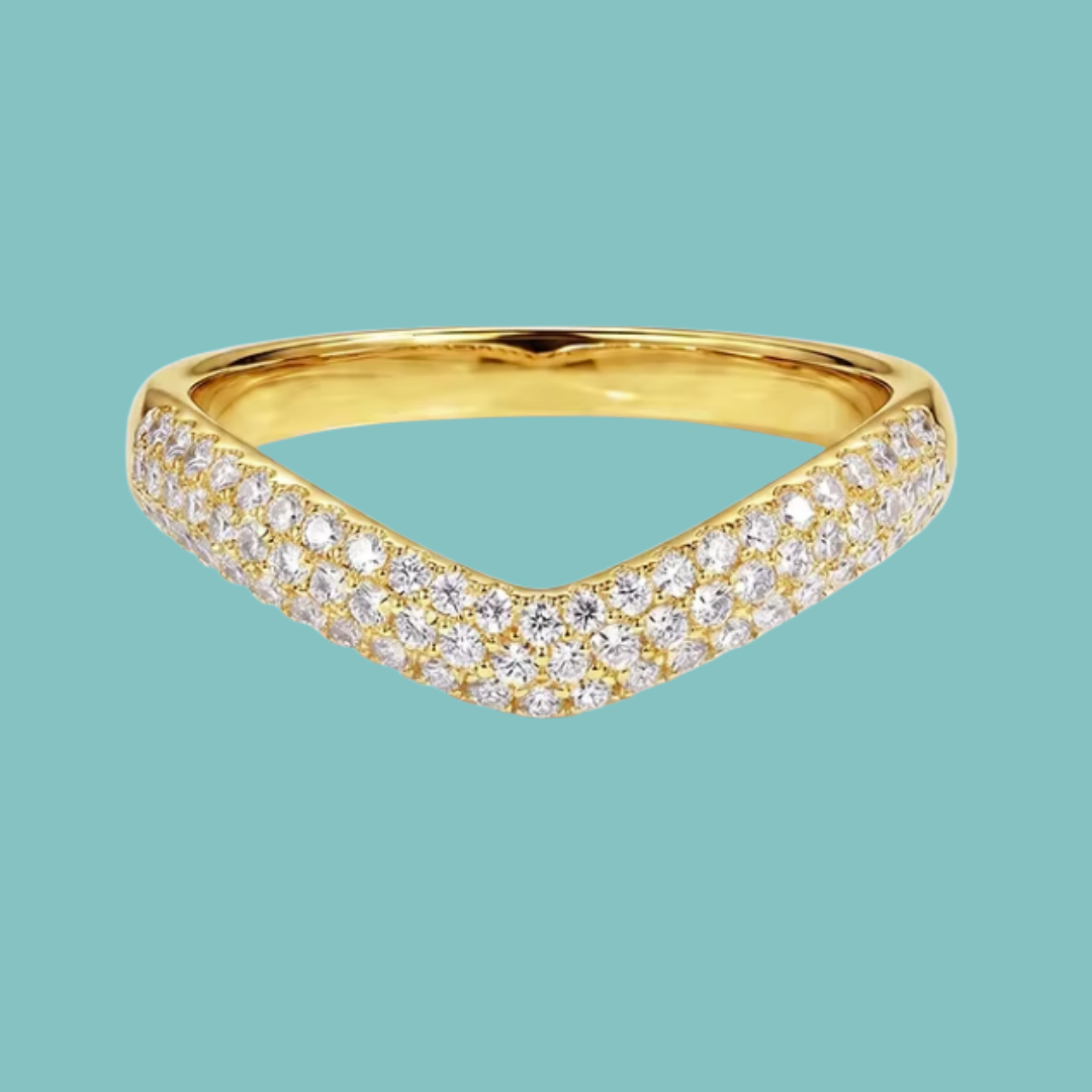 A gold V-shaped pavé ring with clear gemstones, shown on a solid teal background.
