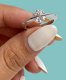 Saturn’s Kiss moissanite ring featuring a round centre stone crossed by a polished silver-toned band, with small side stones.