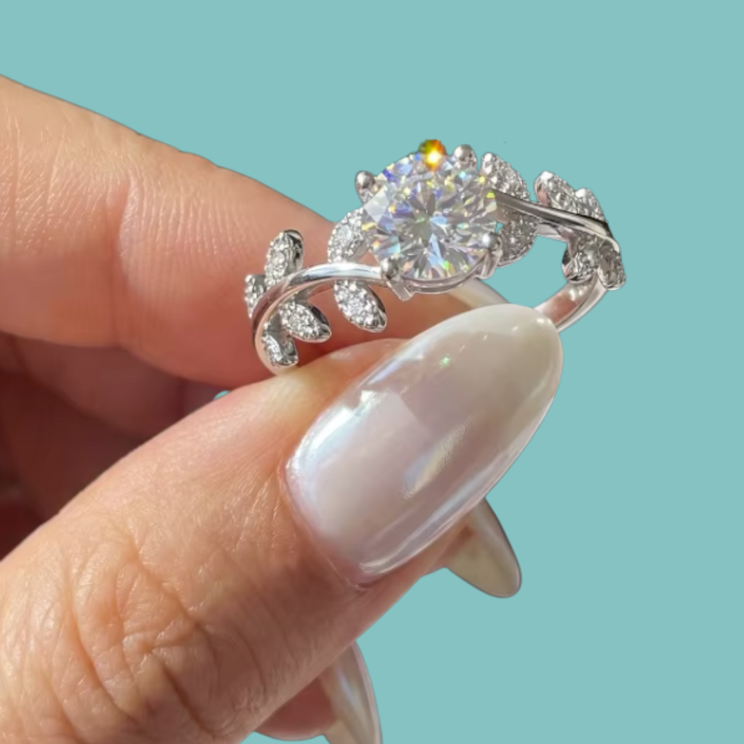 Romantic round moissanite engagement ring with intricate leaf inspired shoulders