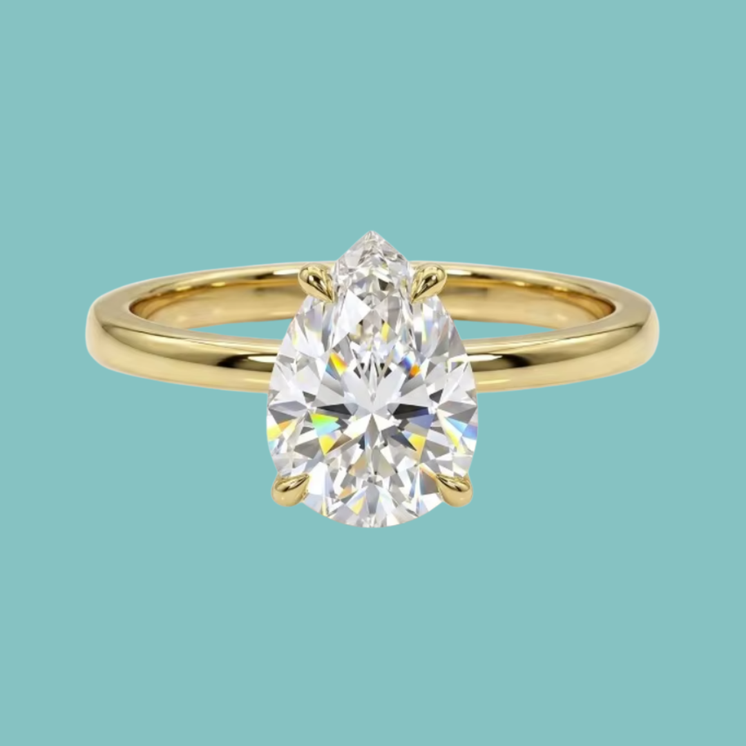 A pear-cut diamond engagement ring in a yellow gold band, centered against a solid light teal background.