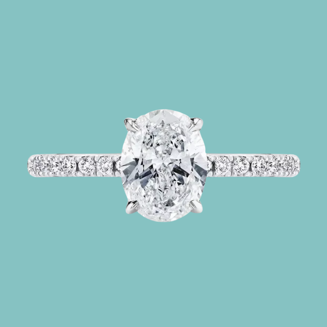 An oval-cut diamond engagement ring with a pavé band, shown against a solid teal background.