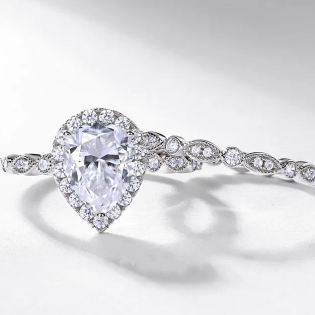 Pear cut moissanite engagement ring set with halo setting and matching band in sterling silver