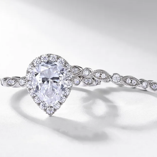 Pear cut moissanite engagement ring set with halo setting and matching band in sterling silver