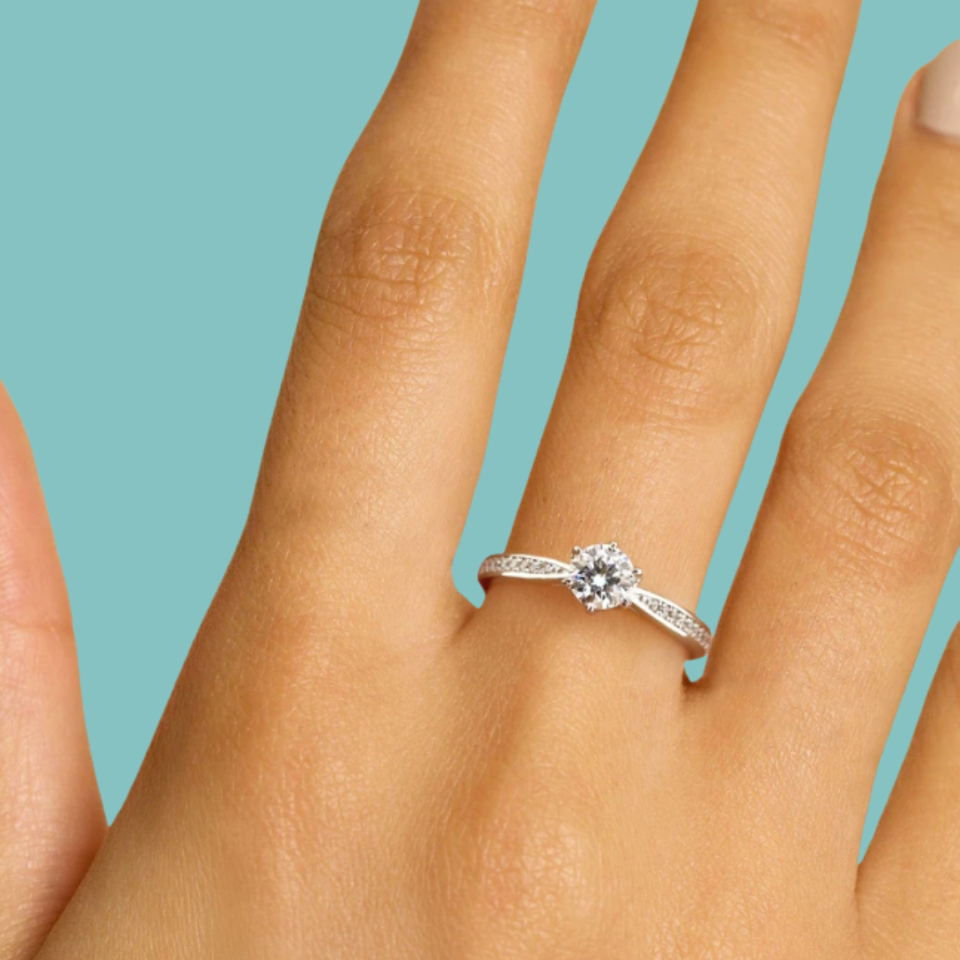 Round cut moissanite engagement style ring with pavé shoulder stones