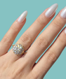 Two-tone moissanite ring featuring a brilliant round centre stone and ornate decorative halo