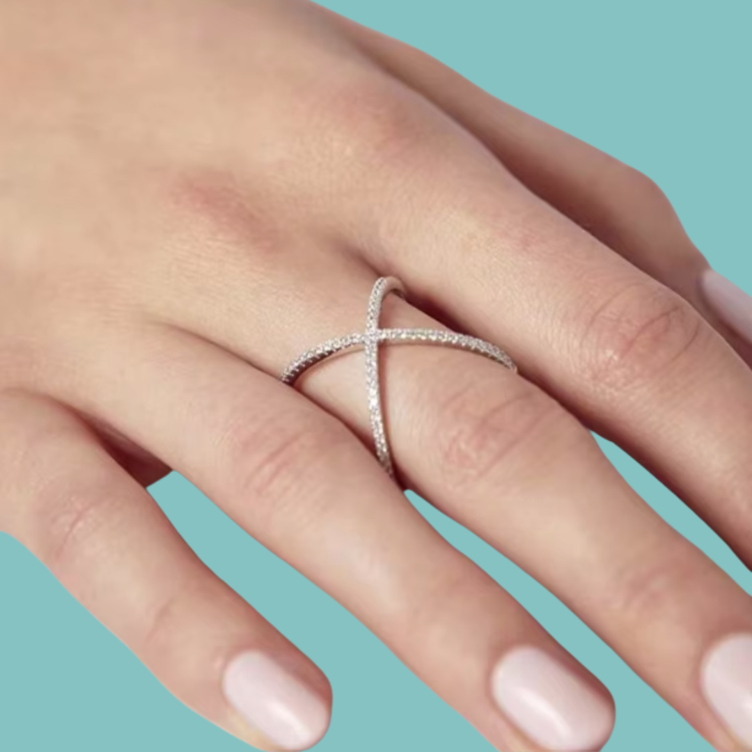 Modern crossed band moissanite ring held between fingers
