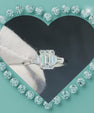 An emerald-cut diamond engagement ring with baguette side stones set in a silver-toned band